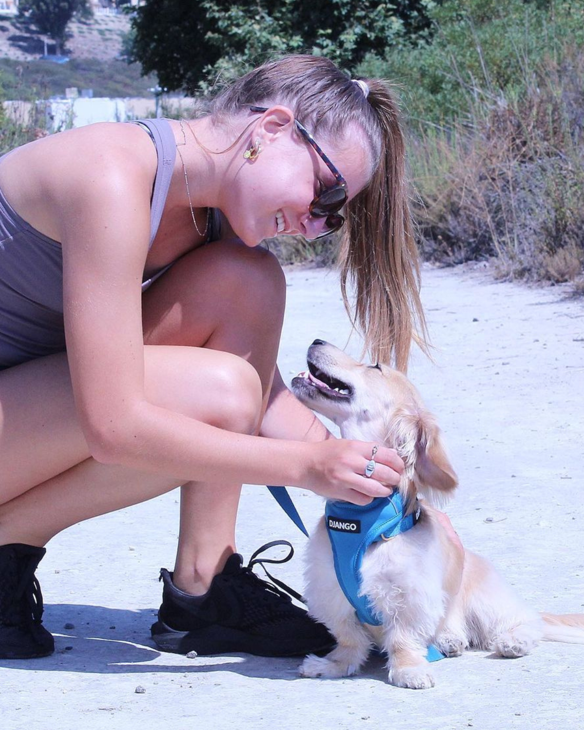 Dog mom giving cuddles to her mini dachshund while taking a hike on a trail. Dog is wearing a blue padded and lightweight harness for adventures