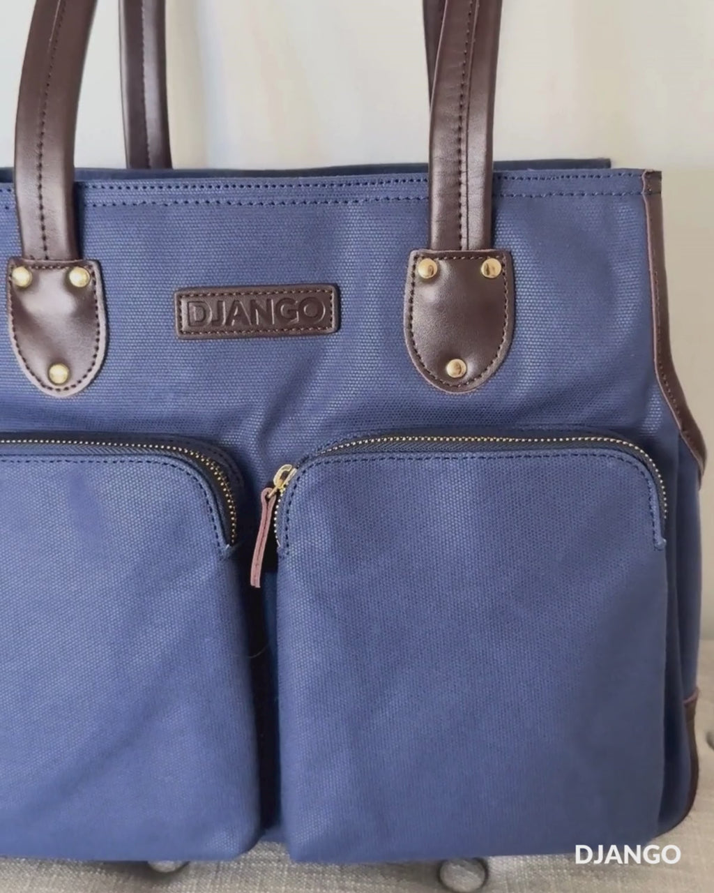 Watch the DJANGO Dog Carrier Tote Bag in action from home to city streets. This beautifully crafted small dog carrier tote and luxury pet purse features a durable 20 oz waxed canvas exterior, genuine leather handles, a supportive base, and a soft interior for comfort on the go. With an open front scoop for visibility, a top zip and safety leash for security, and thoughtful storage throughout, it blends timeless style with everyday function for errands, commuting, and adventures with your dog.
