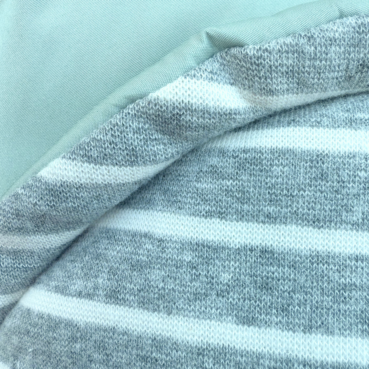 Close up view of soft, white and gray striped lining of a sea foam green winter puffer coat for small and medium dogs